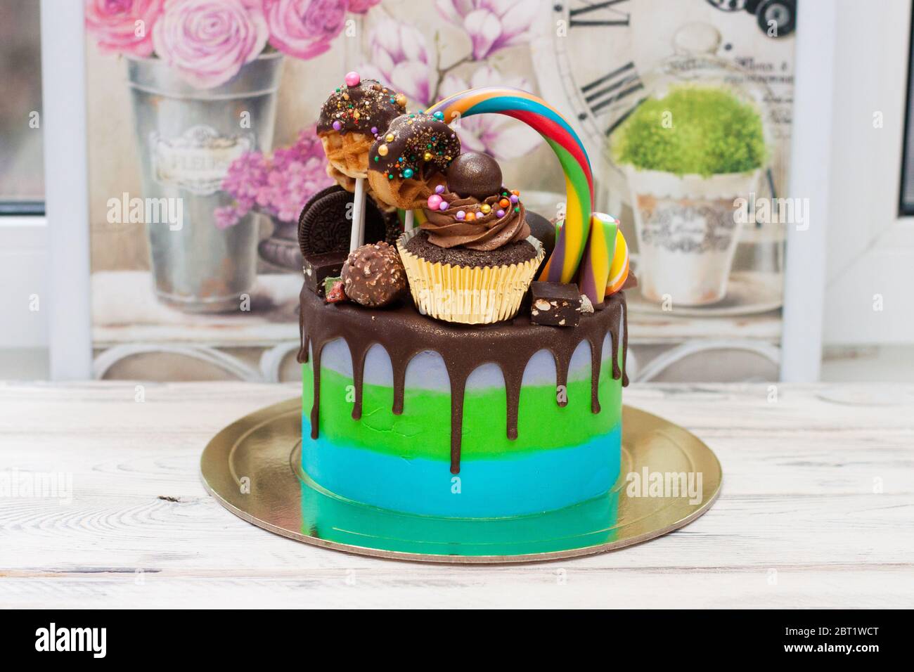 Pastel azul y verde decorado con chocolate fundido, paletas de pastel,  paletas de lollipops, donuts y mini cupcakes Fotografía de stock - Alamy