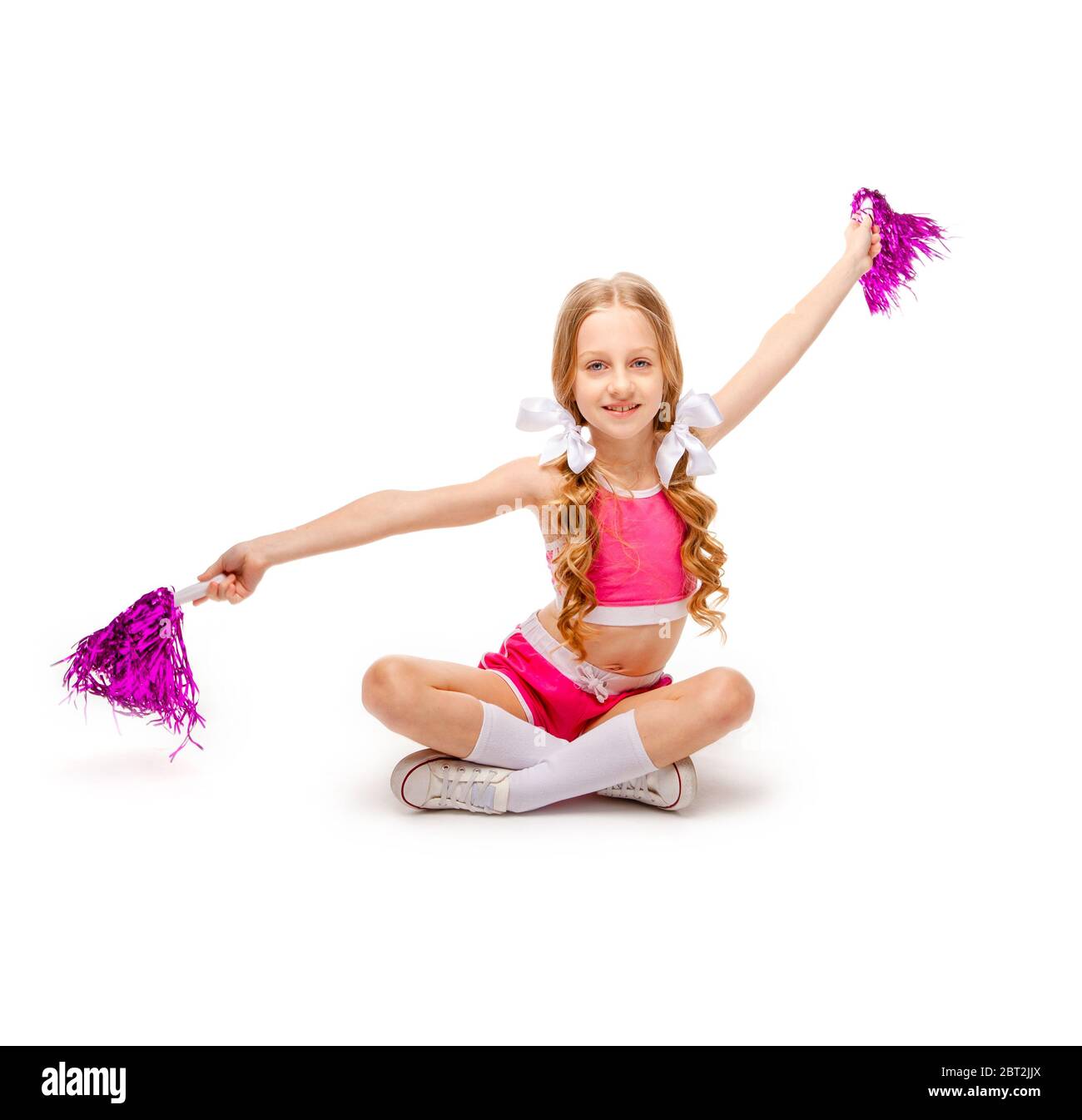 niña de pelo largo en una camiseta de tirantes rosa y ropa de animadora  sentada con piernas cruzadas Fotografía de stock - Alamy
