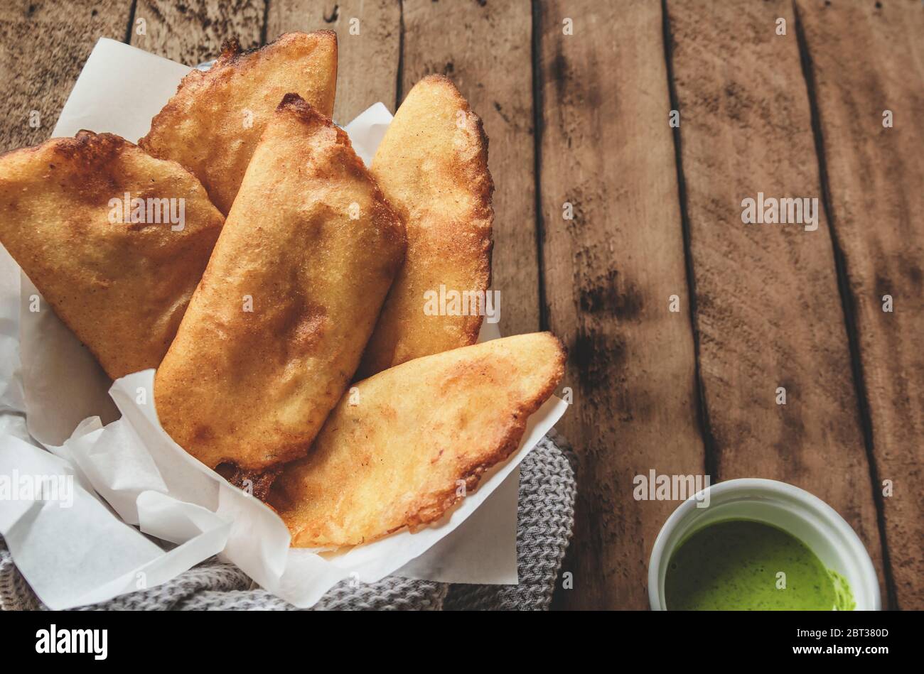 COMIDA VENEZOLANA COLOMBIANA. Tipos venezolanos empanadas de maíz con carne en cuenco de arcilla con salsa de aguacate, empanadas fritas, relleno de pollo y mea Foto de stock