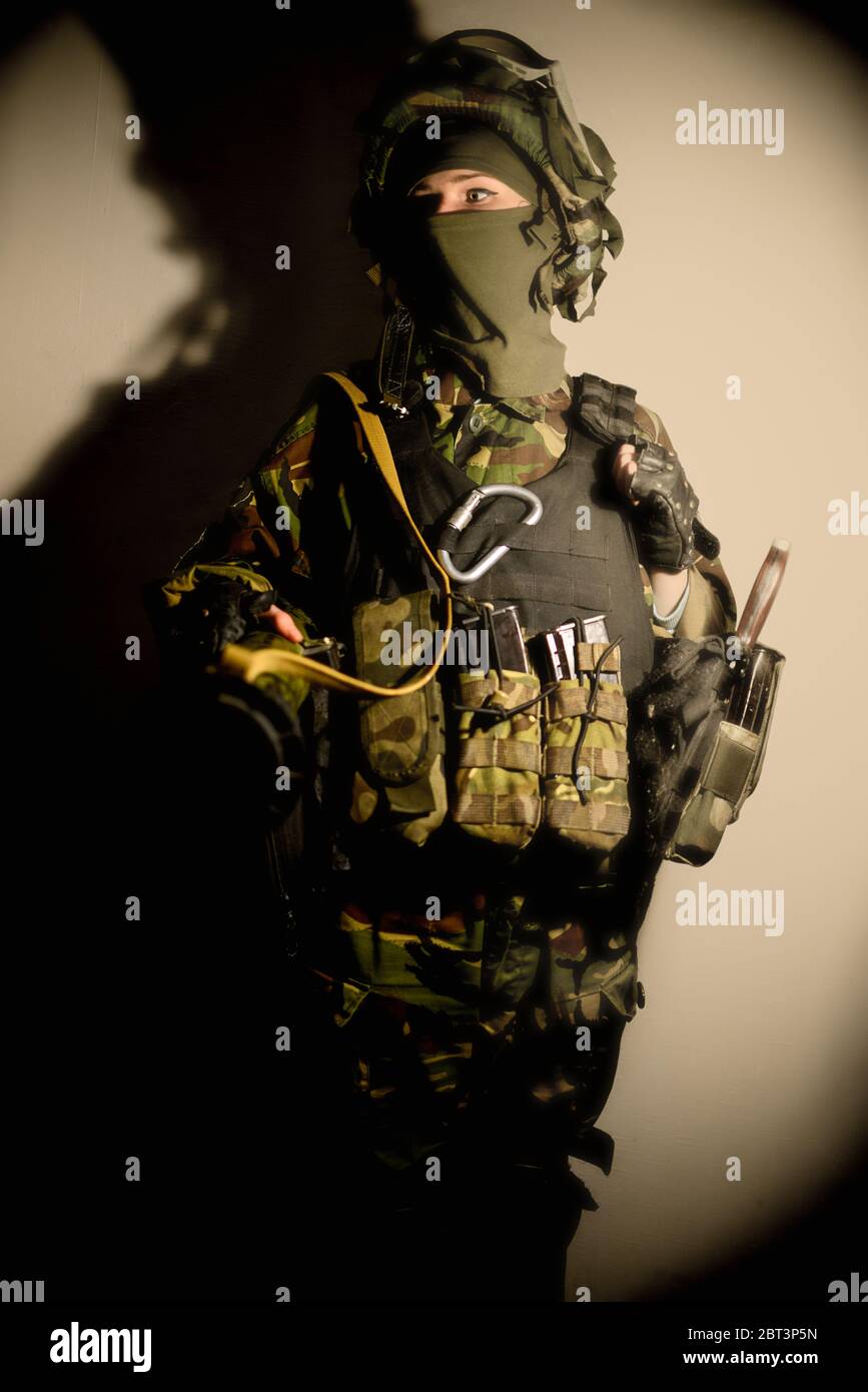 Mujer con ropa militar con máscara sobre fondo claro y con