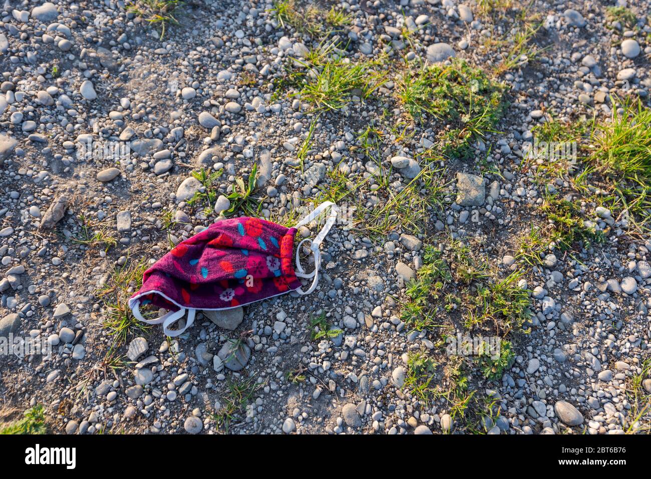 Máscara de protección facial de colores dispuestos en la playa de grava del lago local durante la pandemia de Corona 2020 Foto de stock