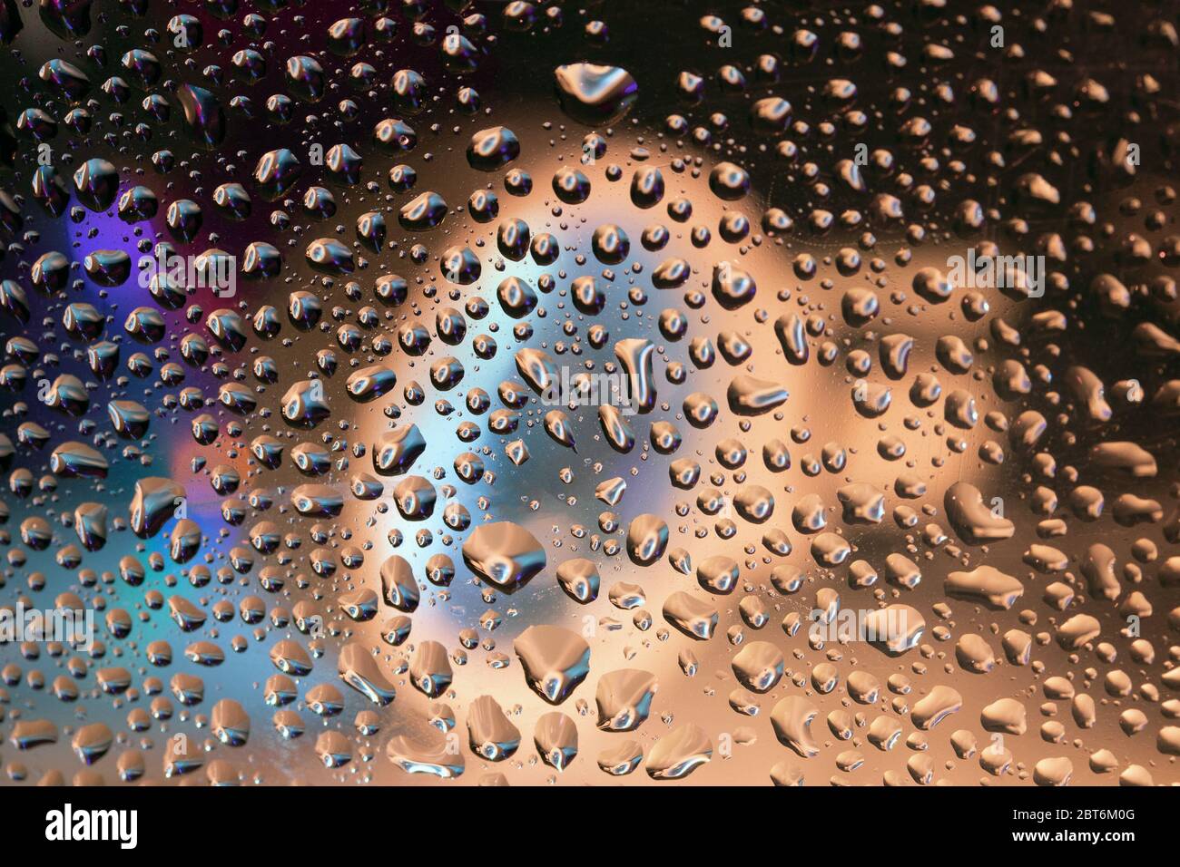Extraordinarias gotas de agua sobre plástico transparente con iluminación, primeros planos. Foto de stock