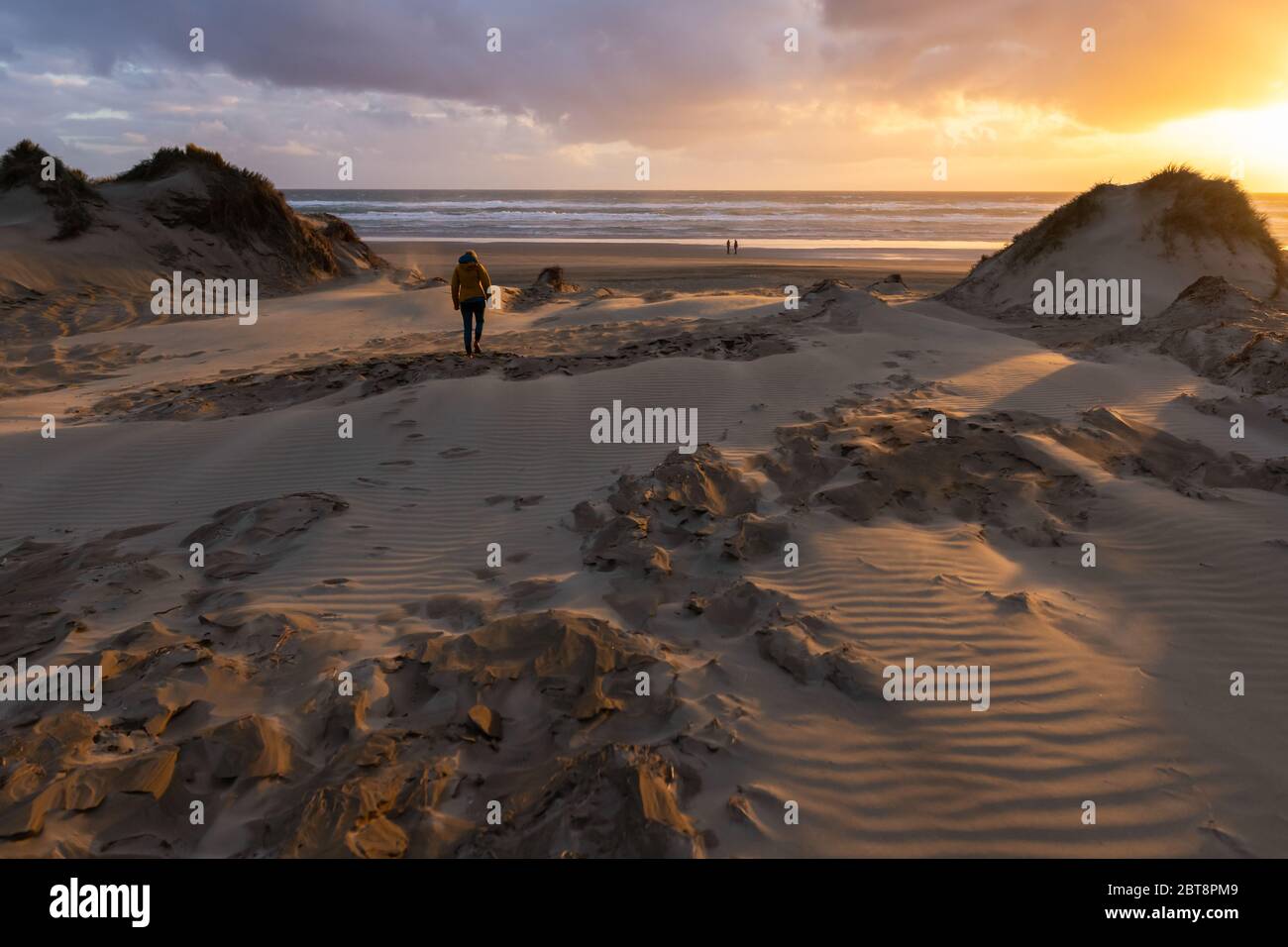 Una mujer se dirige a la playa de 90 millas al atardecer, playa de 90 millas, Nueva Zelanda, octubre de 2019 Foto de stock