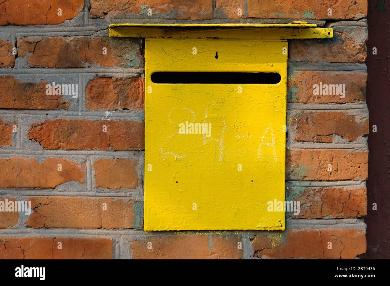 Buzón personal de metal amarillo viejo en una pared de ladrillo rojo. Caja  para recibir cartas y otro correo en papel. Agujero en el cajón para  recibir correspondencia Fotografía de stock -