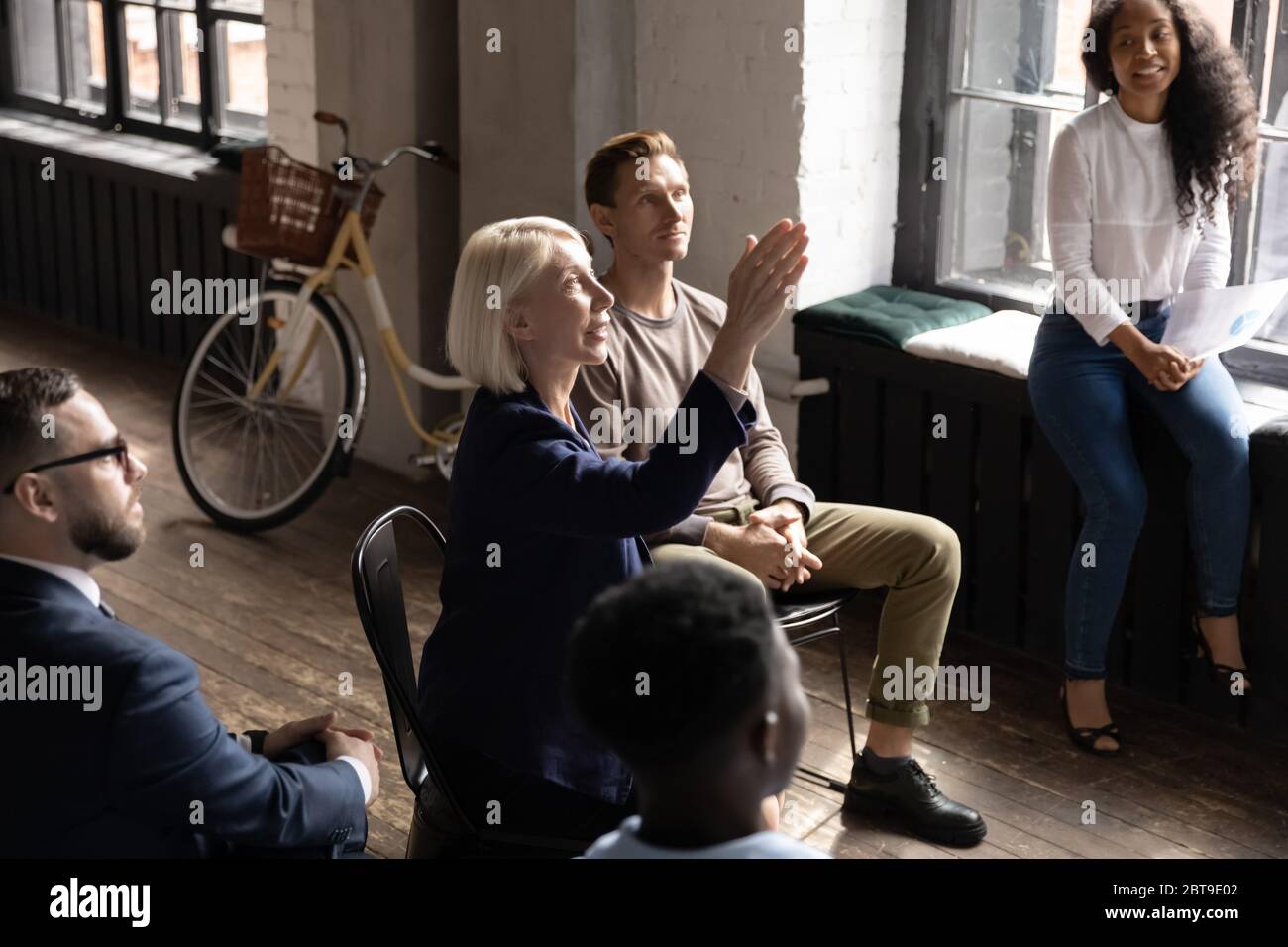 Empresaria de mediana edad que se levanta la mano, haciendo preguntas en la sesión informativa Foto de stock