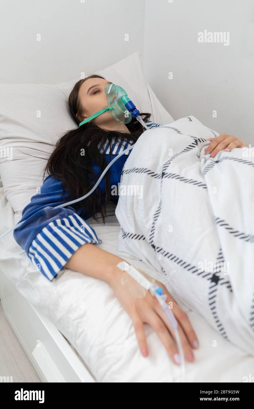 Un adolescente enfermo. Mascarilla de oxígeno. Está en una cama de  hospital. Vestido con un albornoz y cubierto con un edredón Fotografía de  stock - Alamy