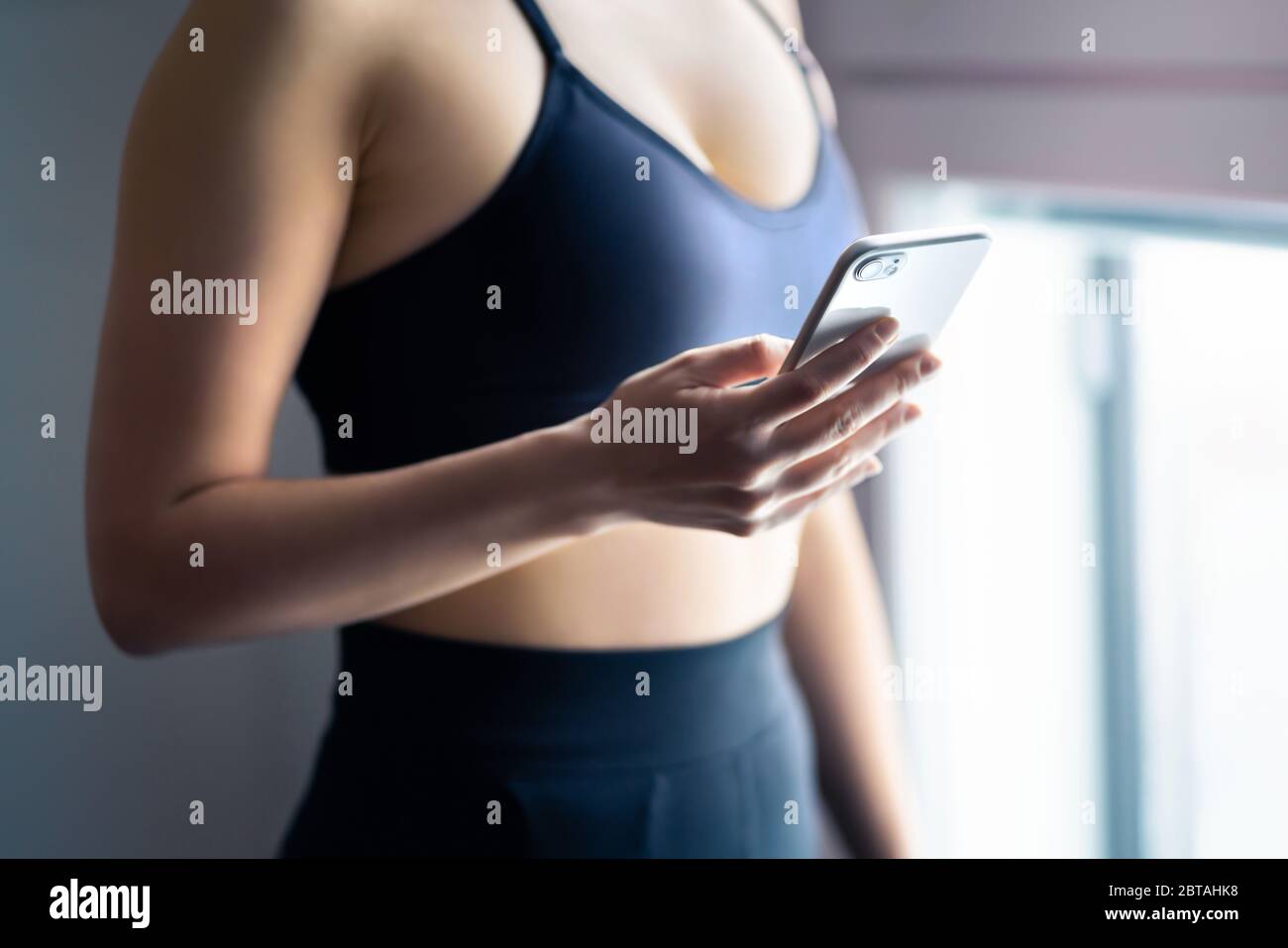 Ajuste a la mujer usando el teléfono. Gimnasio y ejercicio con la aplicación móvil de seguimiento de deportes en el smartphone. Atleta, modelo de fitness, experto en salud, entrenador personal. Foto de stock