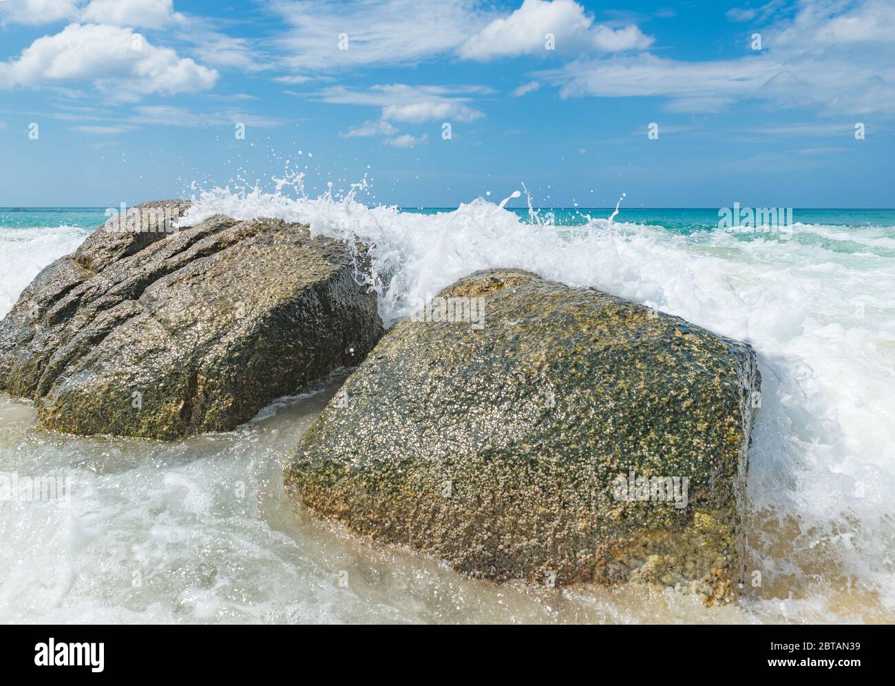 olas rompiendo en grandes rocas en una playa en tailandia Foto de stock