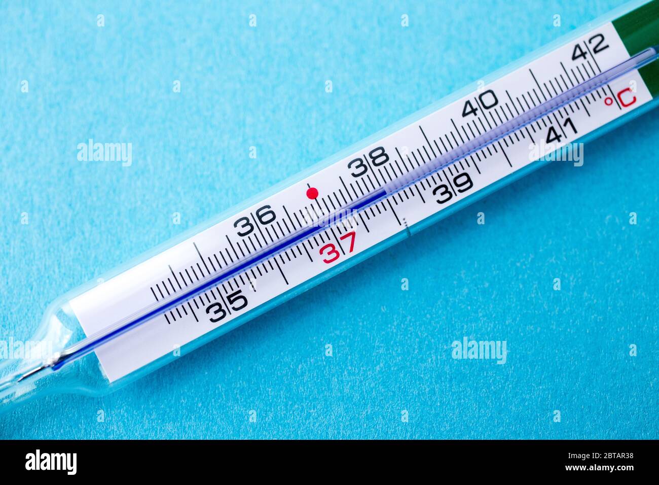 Termómetro analógico de mercurio con 37,7 °C de temperatura, fiebre, gripe,  virus corona, covid19, sobre fondo azul Fotografía de stock - Alamy