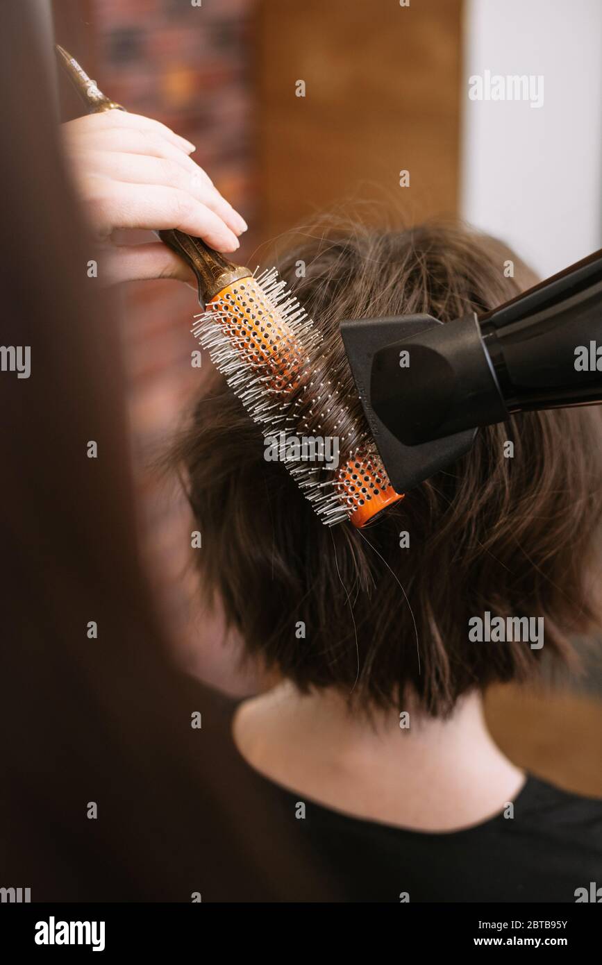 La peluquería hace el peinado para el pelo corto con un secador de pelo y  cerdas redondas. Mujer haciendo peinado en un salón de belleza Fotografía  de stock - Alamy