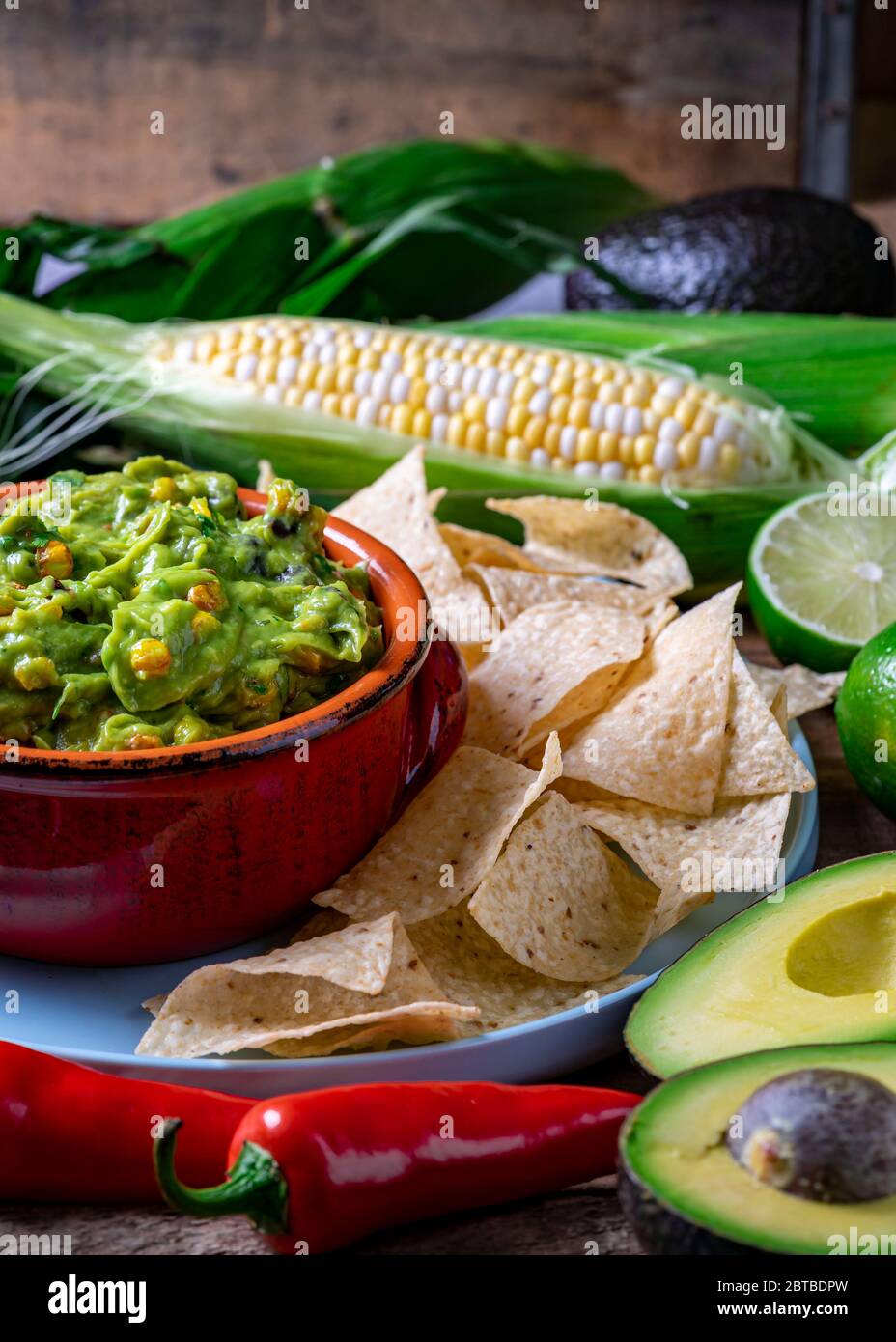 Salsa de guacamole con maíz asado e ingredientes crudos Foto de stock