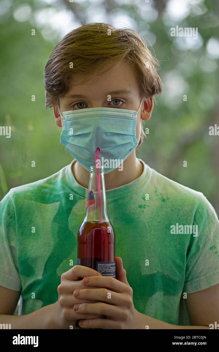Niño usando mascarilla de respiración bebiendo de una botella usando una pajita, Alemania Foto de stock