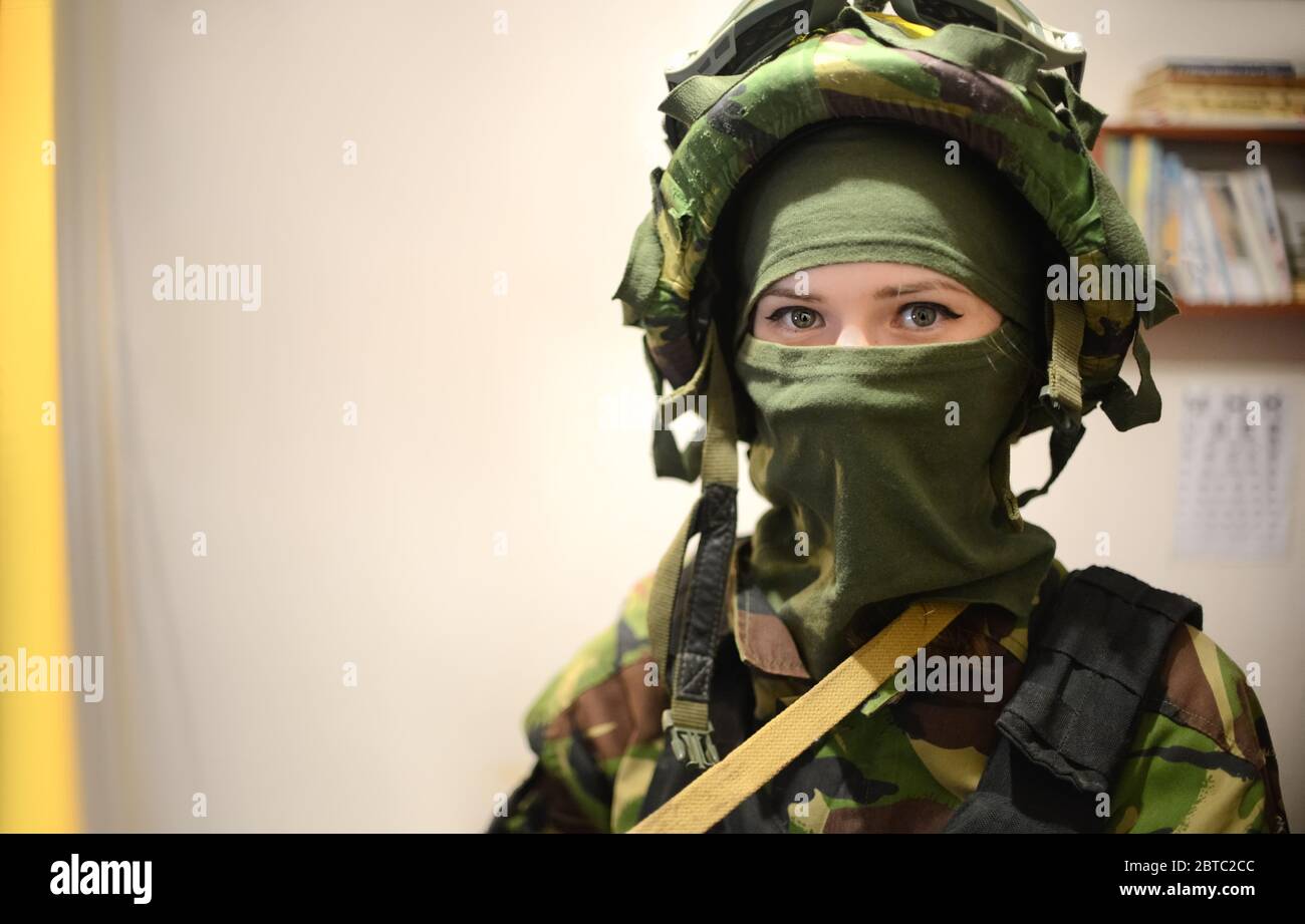 Mujer con ropa militar con máscara sobre fondo claro y vignetting. Mujer soldado en camuflaje en concepto de guerra. Retrato de mujer Fotografía de stock -