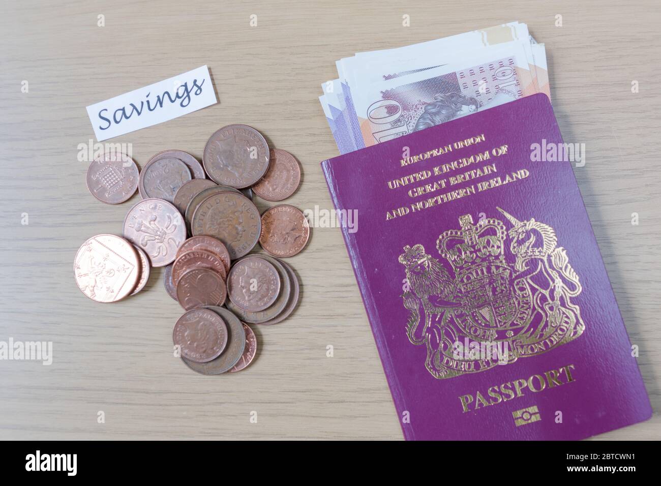 Los centavos del Reino Unido y el pasaporte británico uno al lado del otro en una mesa que simboliza los viajes y los ahorros Foto de stock