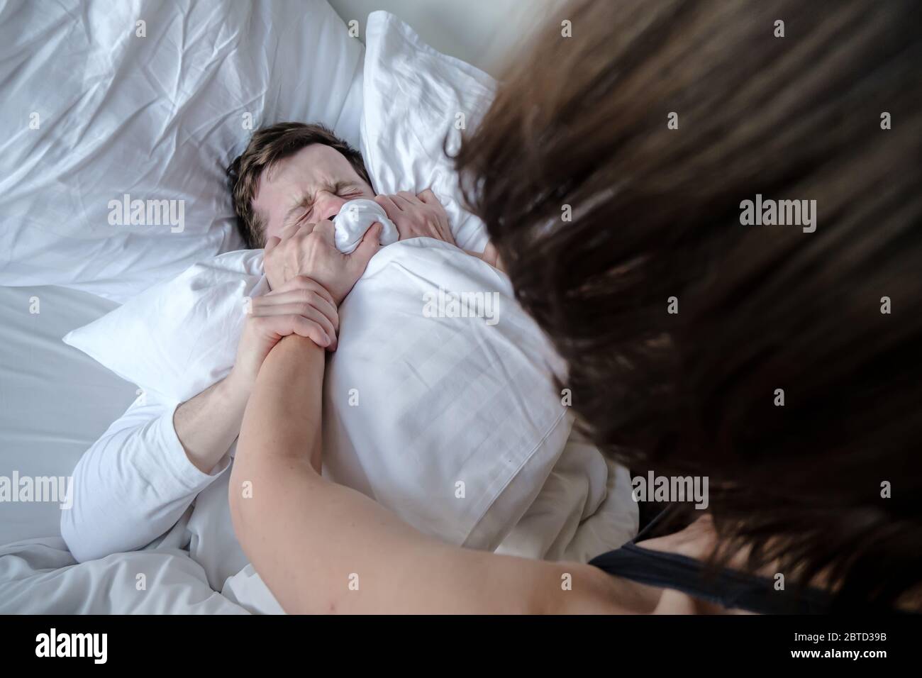 secundario Asociación Poder Violencia doméstica. Las manos femeninas ahogan a un hombre asustado con  una almohada después de una pelea familiar, por la mañana en cama. Vista  superior Fotografía de stock - Alamy