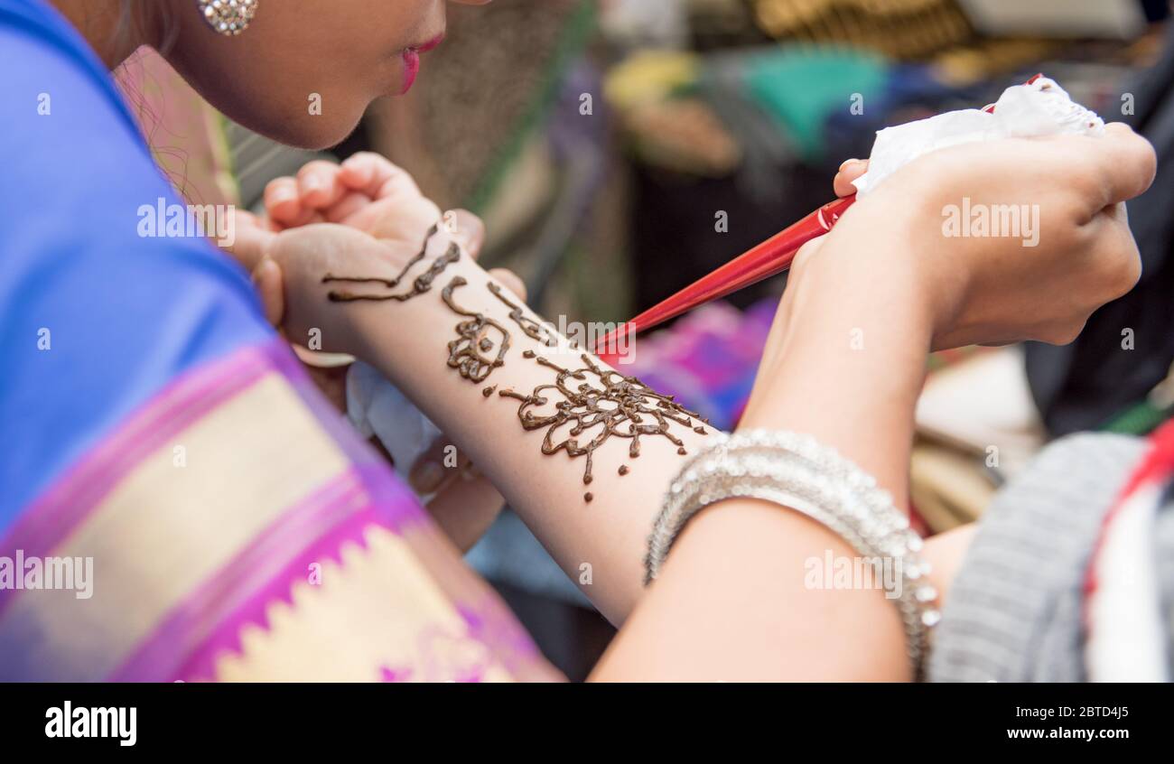 Artistas aplicando tatuaje de henna en manos de mujeres. Mehndi es arte tradicional de la decoración India Foto de stock