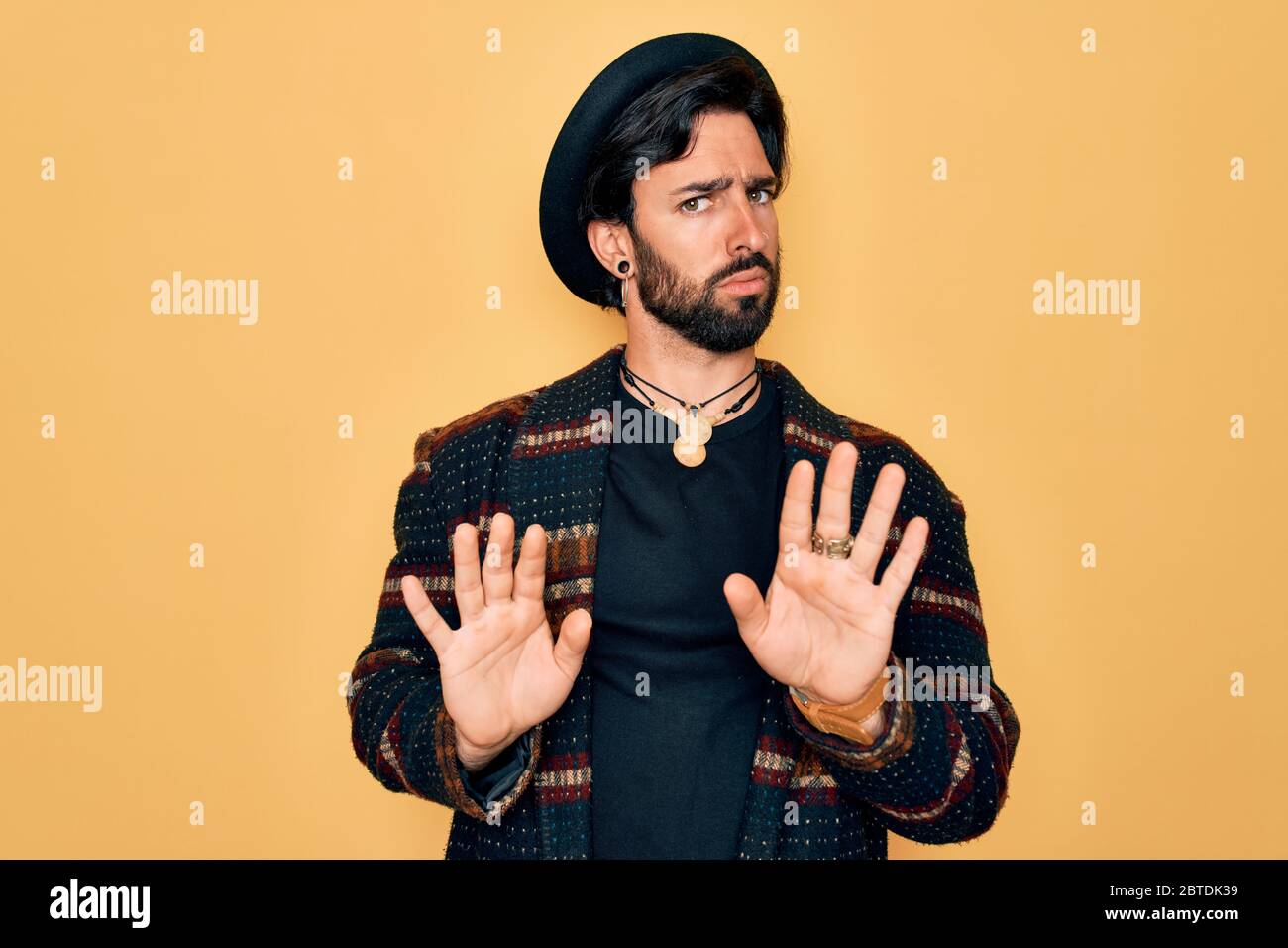 Joven hombre bohemio hispano guapo con estilo hippie sombrero boho moviéndose las manos palmas mostrando rechazo y negación con miedo y Fotografía de stock - Alamy