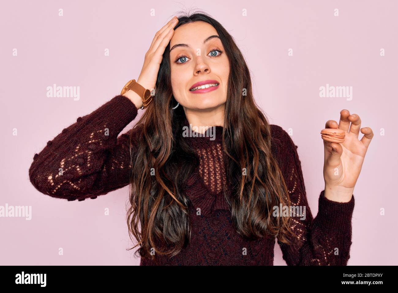 Joven hermosa mujer con ojos azules usando gafas comiendo macaron