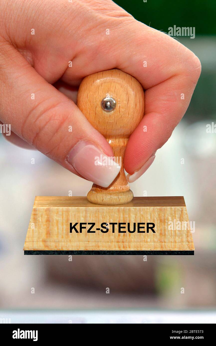 Mano con sello de madera impreso con KFZ-Steuer Foto de stock