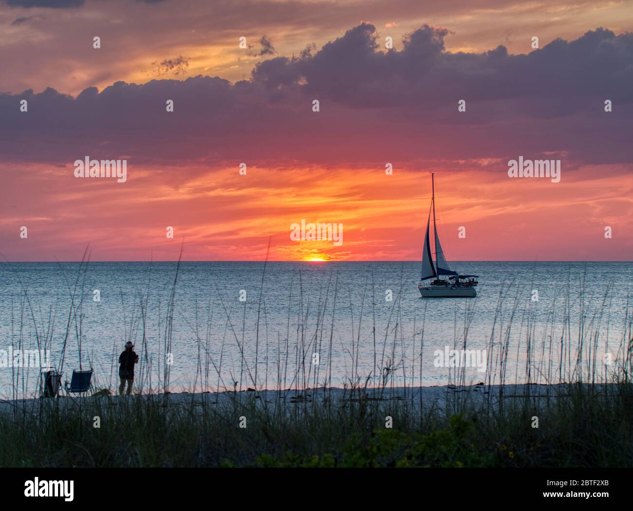 Velero en el Golfo de México al atardecer con un cielo naranja en la playa Nokomis en la costa del Golfo de Florida Foto de stock