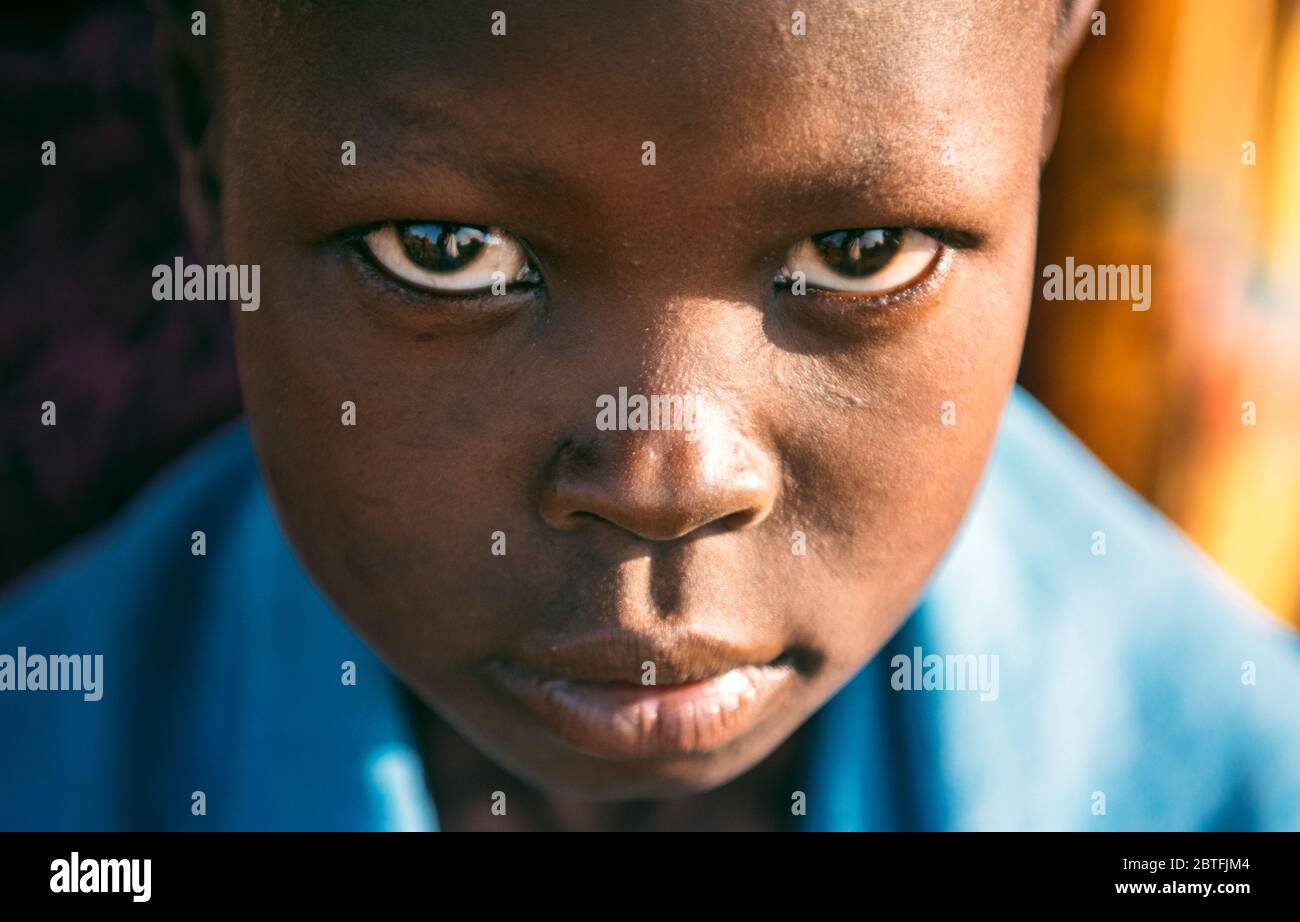 TRIBU BOYA, SUDÁN DEL SUR - 10 DE MARZO de 2020: Niño envuelto en tela azul mirando la cámara mientras vivía en la aldea de Boya Tribe en Sudán del Sur, África Foto de stock
