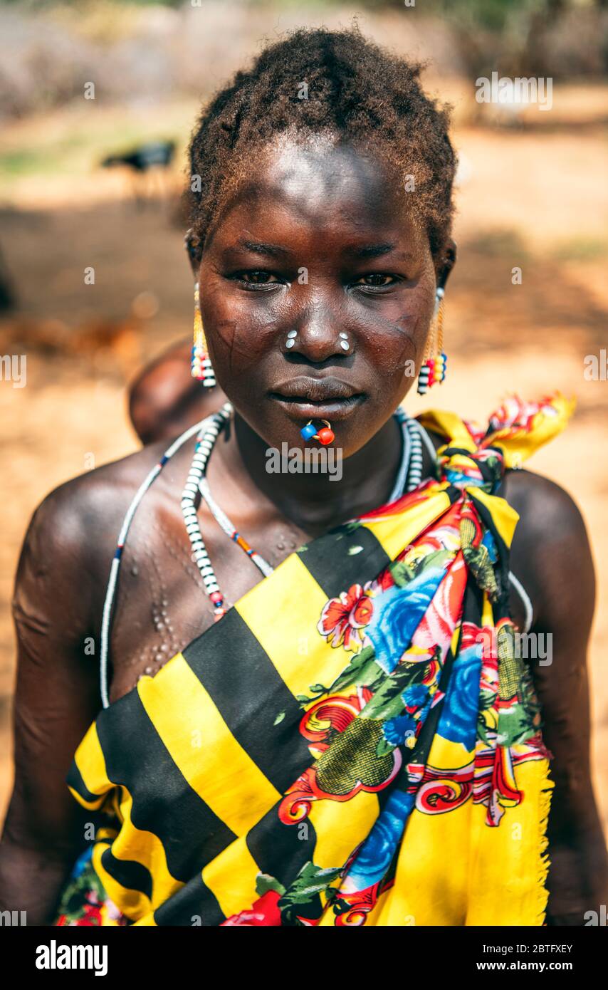 TRIBU BOYA, SUDÁN DEL SUR - 10 DE MARZO de 2020: Mujer en ropa tradicional de colores y accesorios con perforación ritual y modificaciones de cicatrices mirando Foto de stock