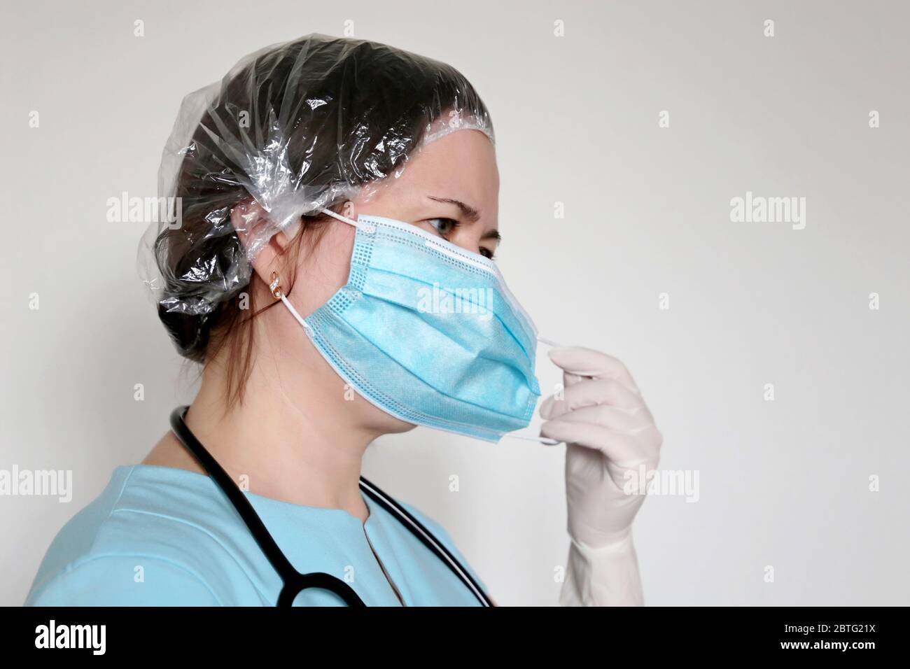La mujer en guantes de látex retira la máscara médica. Doctor cansado después de un trabajo duro, concepto de tratamiento con covid-19 coronavirus Foto de stock