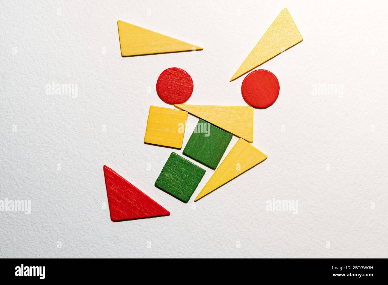 Diferentes formas coloridas de madera sobre fondo blanco. Formas geométricas rojo, verde, amarillo, vista superior. Concepto de geometría. Espacio de copia. Tarea lógica educativa para los niños. Disposición plana. Foto de stock