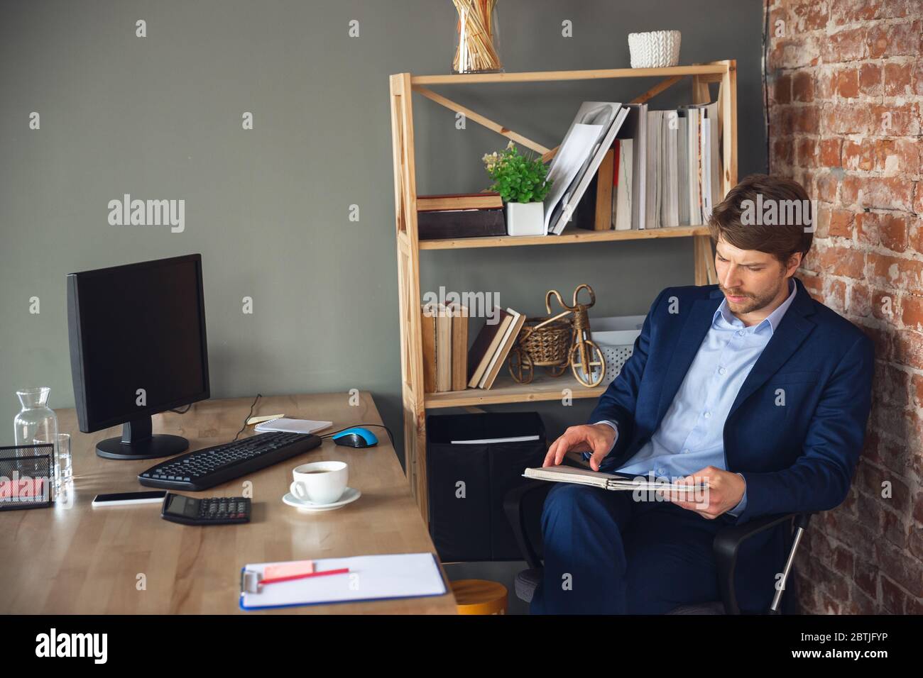 Revisar documentos, tareas, papeleo. Joven, gerente vuelve a trabajar en su oficina después de la cuarentena, se siente feliz e inspirado. Volviendo a la vida normal. Negocio, finanzas, concepto de emociones. Foto de stock