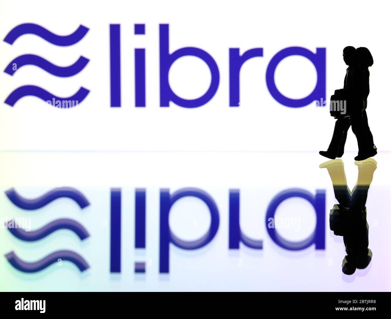 Siluetas delante del logo de Libra un blockchain moneda digital por Facebook (sólo para uso editorial) Foto de stock