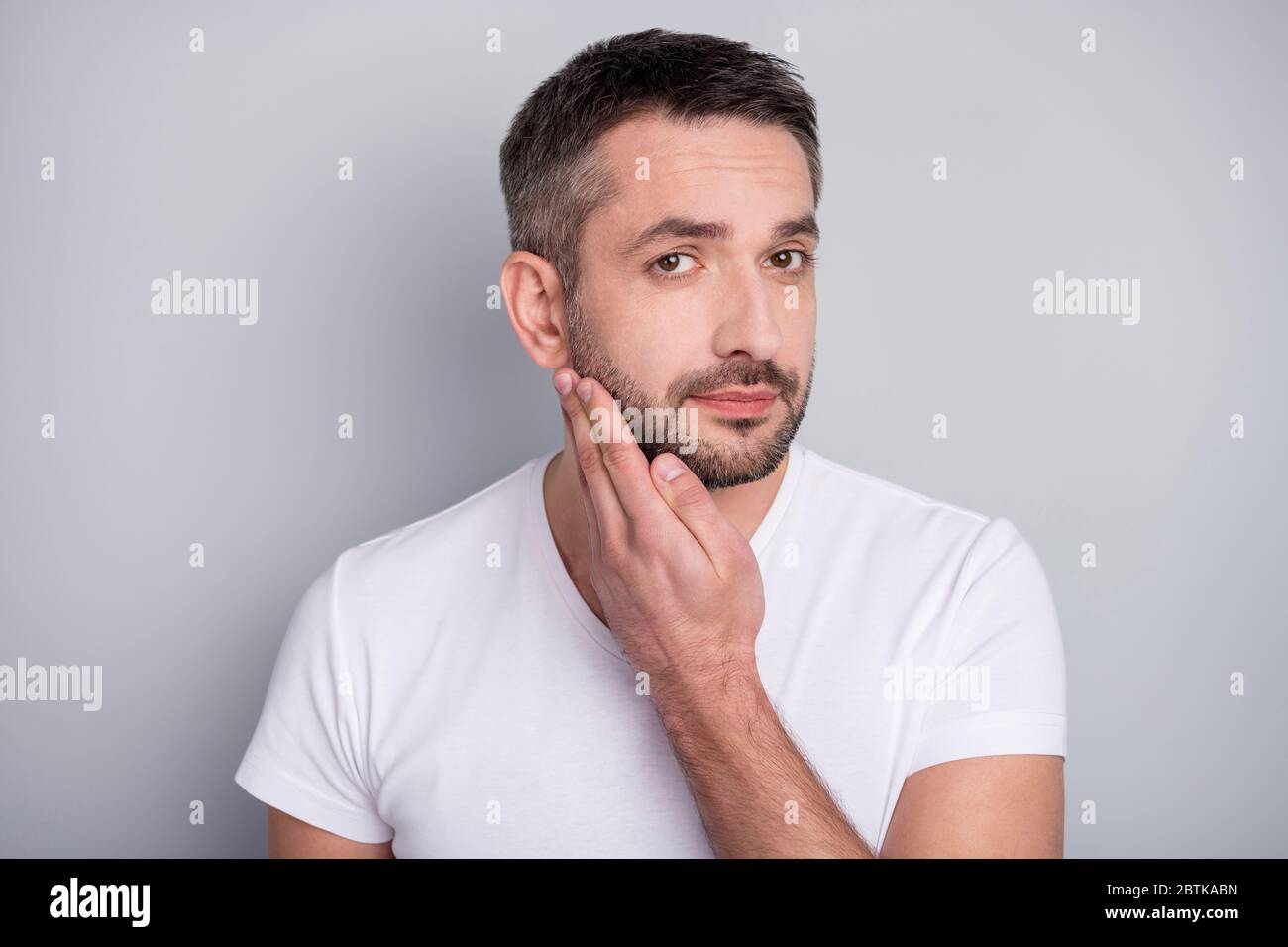 Primer plano retrato de su él bonito y bien cuidado hombre moreno tocando  cerdas de pelo sin afeitar aisladas sobre fondo gris claro color pastel  Fotografía de stock - Alamy