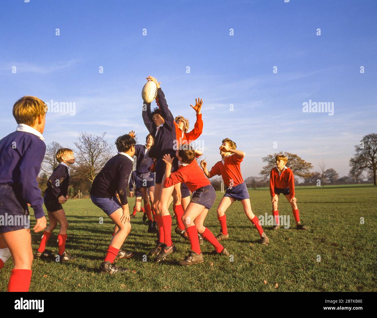 Chicos saltando en el lineout en el partido de rugby de la escuela, Surrey, Inglaterra, Reino Unido Foto de stock
