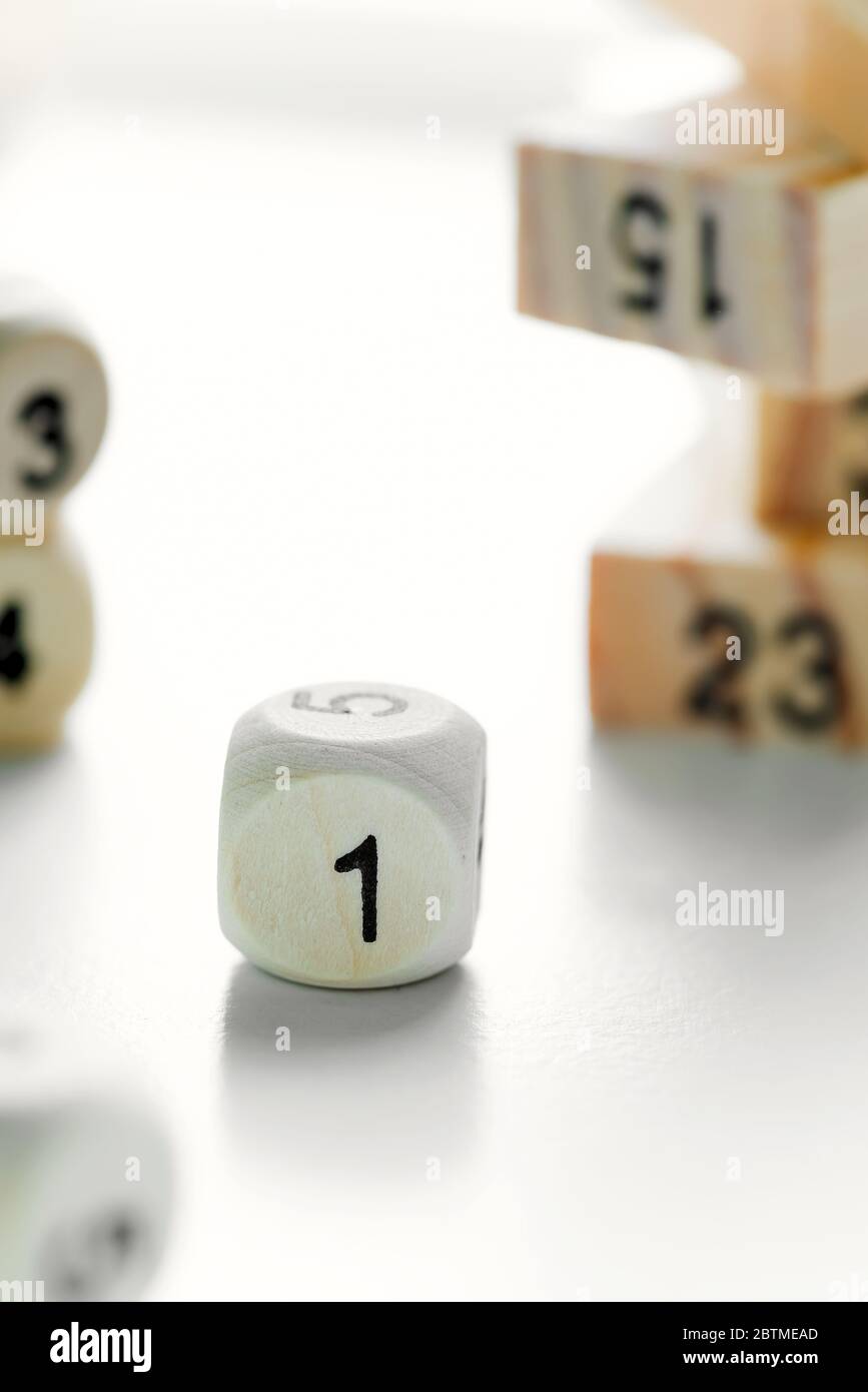Cubo de dados de madera con número en la cara sobre un fondo gris claro con  torre borrosa de bloques de juego Jenga. Concepto de liderazgo, trabajo en  equipo y gro Fotografía