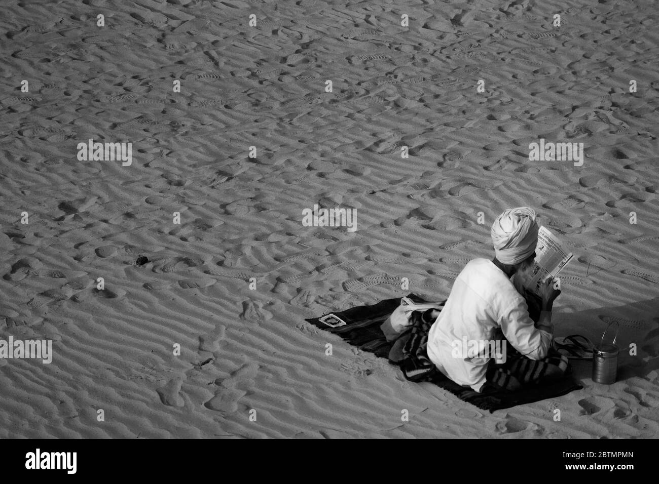 Un hombre viejo con cara oculta leyendo el periódico en la playa Foto de stock