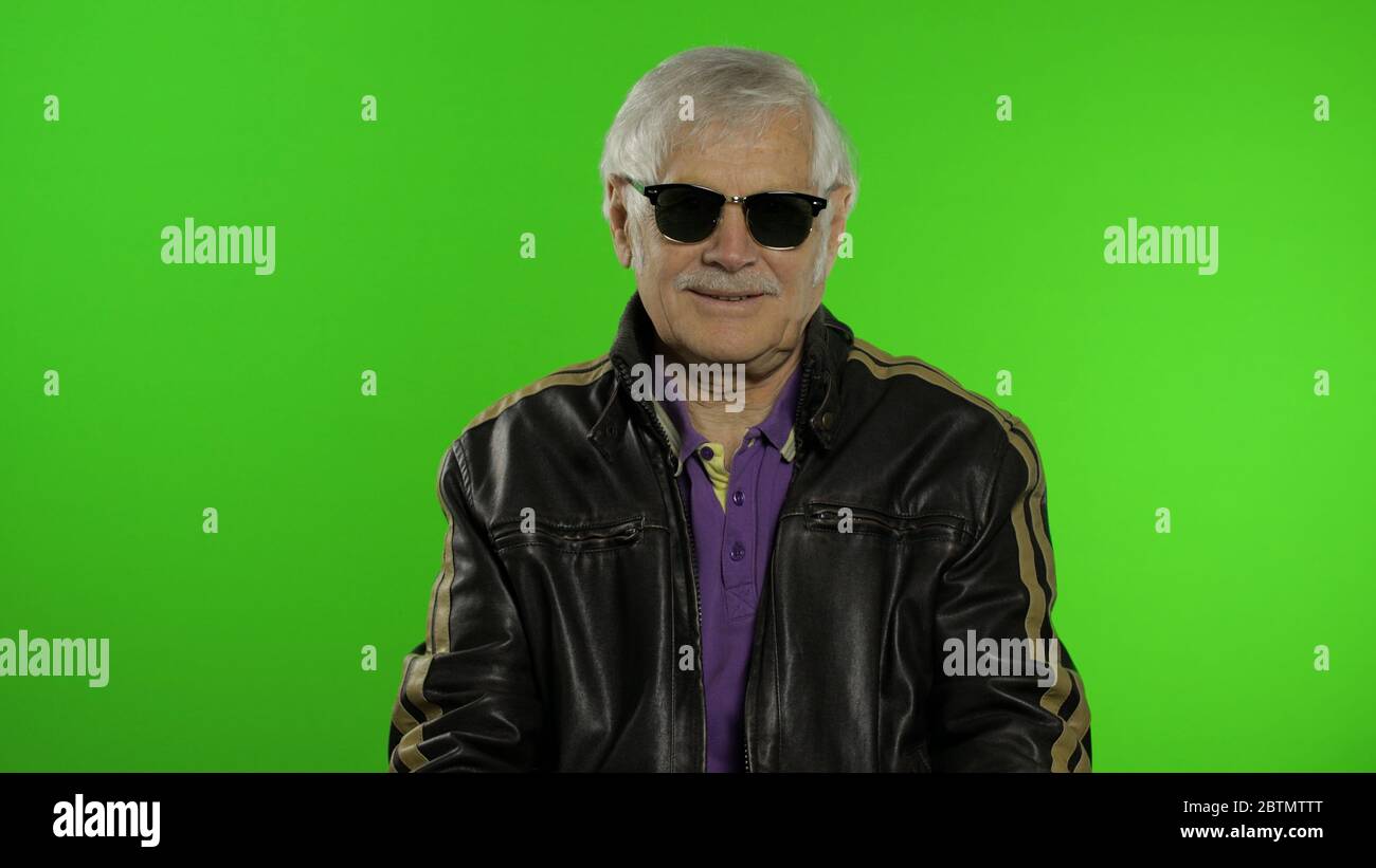 Anciano abuelo con estilo caucásico rockero y biker hombre maduro en gafas  de sol sobre fondo clave de croma. Abuelo mayor en chaqueta de cuero de  moda. Pantalla verde Fotografía de stock -