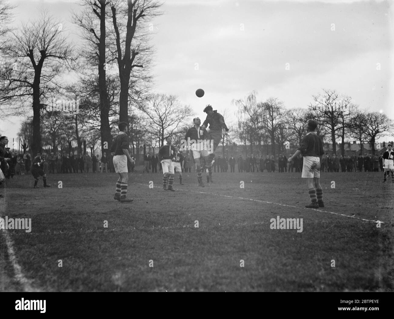 Fútbol en el parque Longlands. Dos jugadores compiten por la pelota en el aire. 1936 Foto de stock