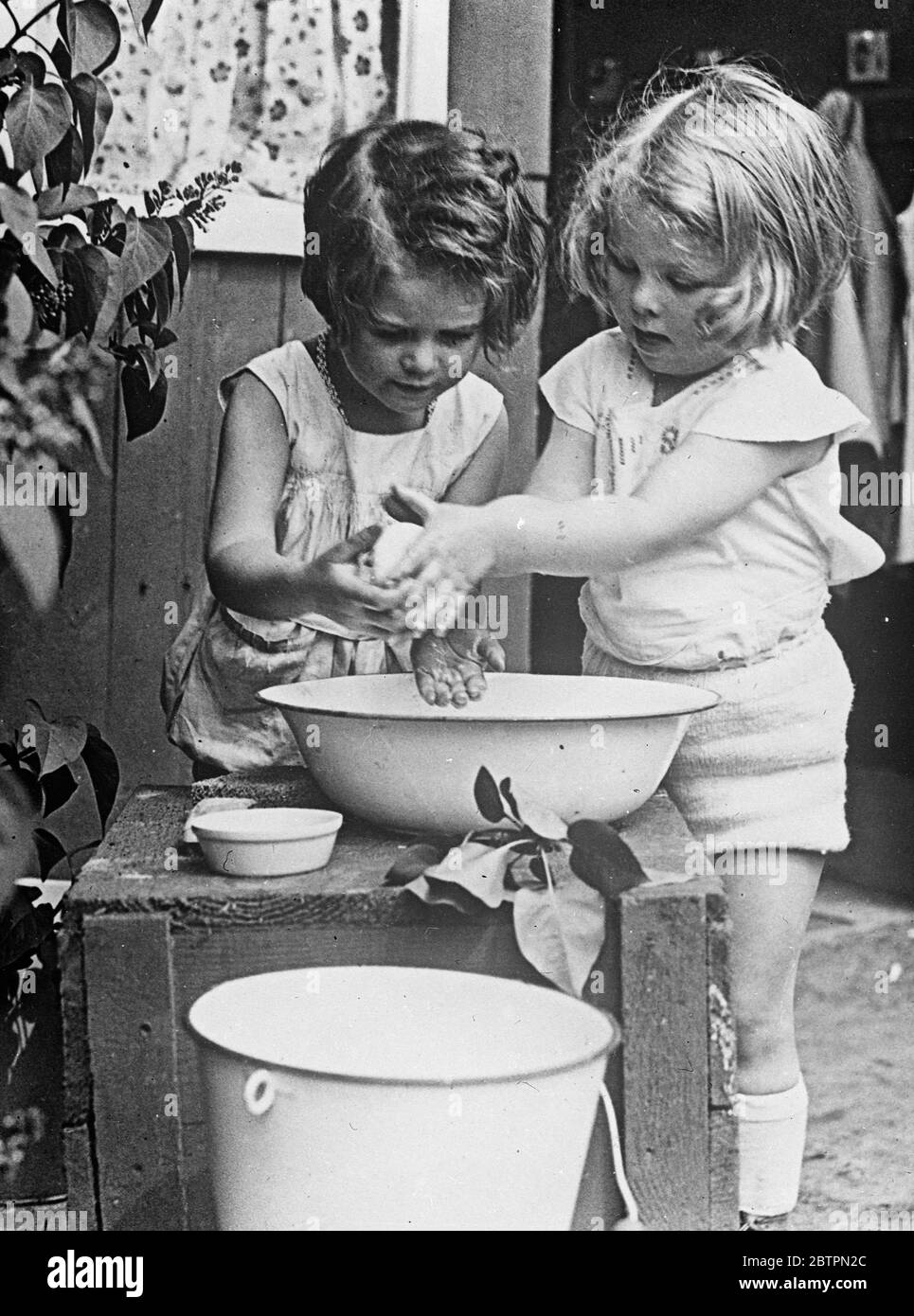 Jabón y agua. La distribución equitativa de agua y jabón era motivo de preocupación para estas dos niñas de bebés con cabeza de choque mientras se preparaban para la cena en su casa de Berlín. Foto de stock