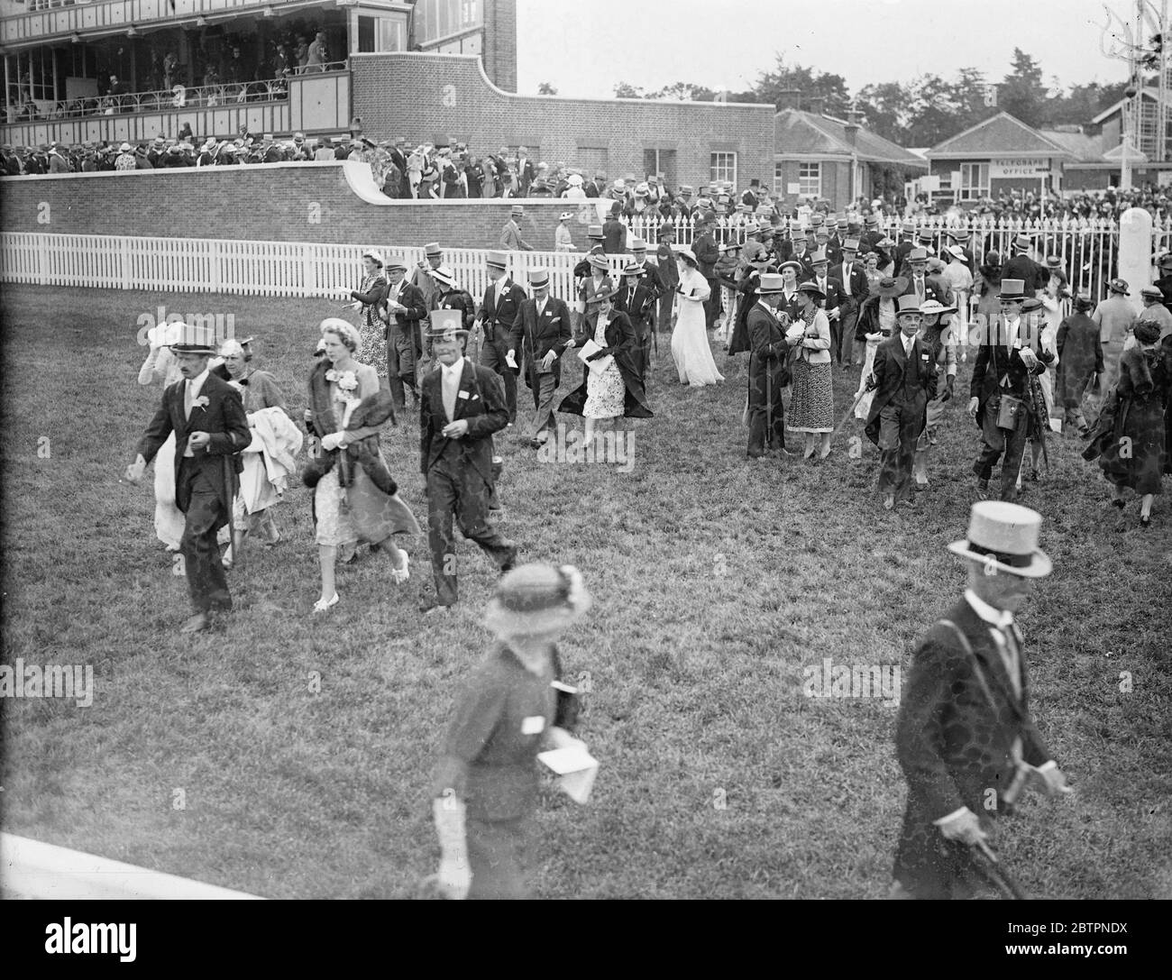 Desfile de moda en Ascot. Muestra de fotos: La multitud de moda que cruza el campo en el segundo día de la reunión de Ascot. 16 de junio de 1937 Foto de stock