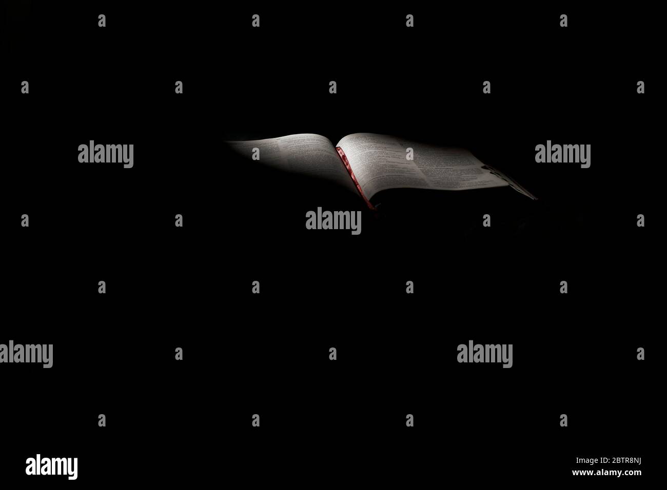 Estudio de libro abierto de la Biblia con una iluminación dramática