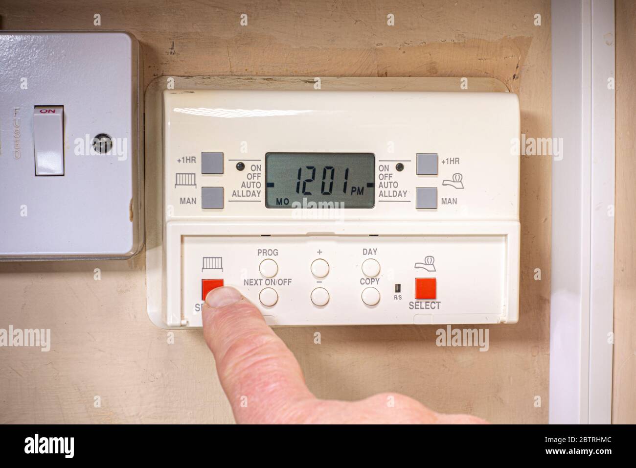 Cerrar PDV tiro de un dedo presionando un botón para activar un hogar,  sistema de calefacción central en un viejo programador / temporizador  Fotografía de stock - Alamy