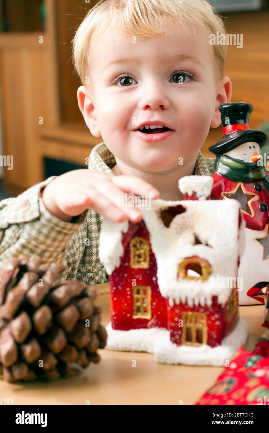 Zweijaehriger Junge mit Weihnachtsdekoration, Lebkuchenhaus, MR: Sí Foto de stock