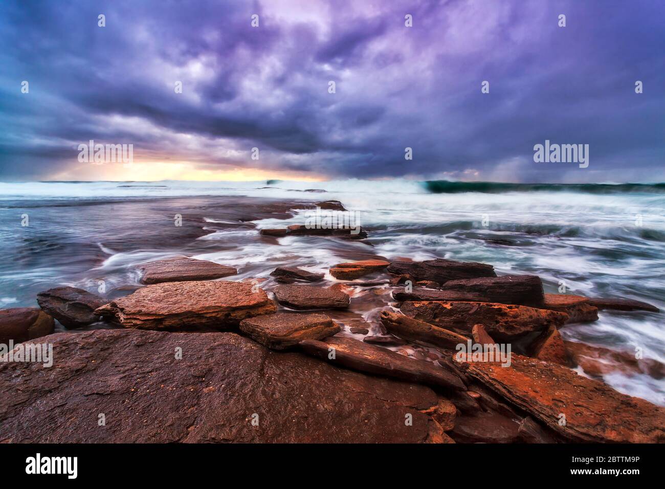 Rocas de arenisca erosionadas planas de las playas del norte de Sydney al amanecer. Foto de stock