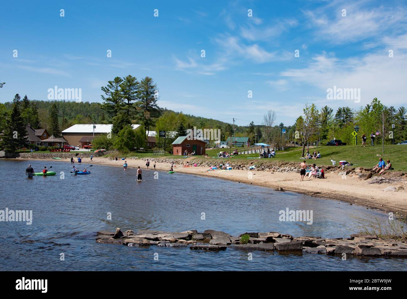 La gente toma el sol, nadando y vadeando en la playa del pueblo de