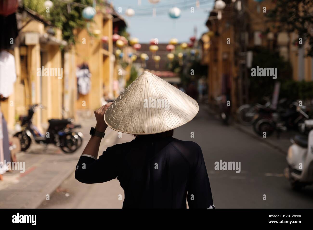 Hermosa niña que lleva sombrero de vietnam o Non la y visita turística en el pueblo Heritage en Hoi An ciudad en Vietnam Foto de stock