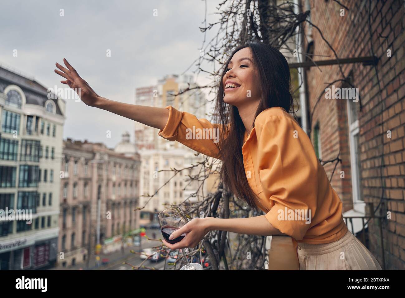 Alegre señora de pie en el balcón y saludar a un amigo Foto de stock