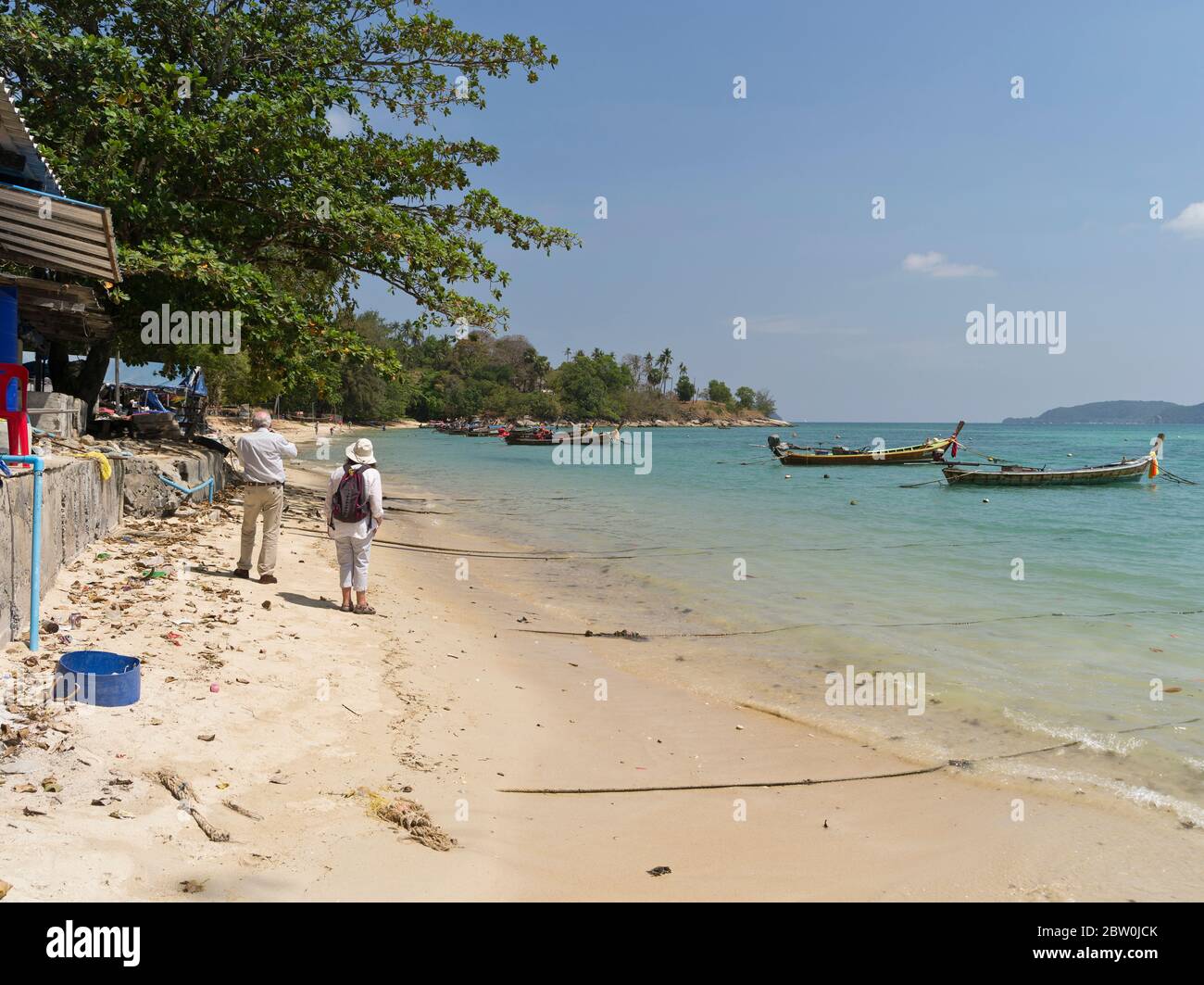 dh Rawai playa PHUKET TAILANDIA Pareja de turistas tomando una fotografía de pesca de cola larga barcos turistas vacaciones tailandés Foto de stock