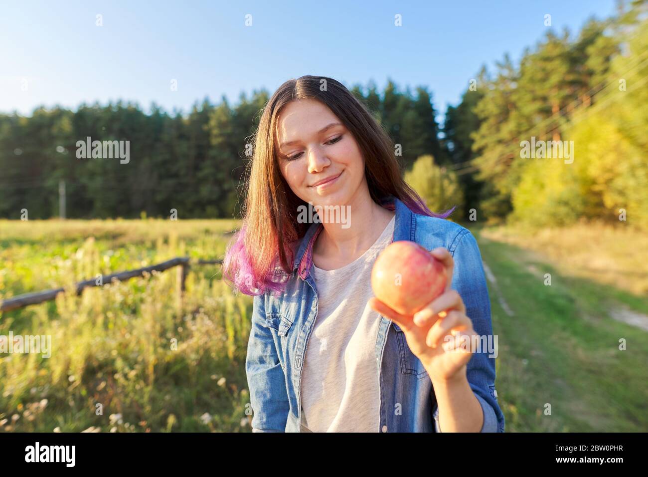 Hermosa niña adolescente con manzana roja, feliz mujer joven en la naturaleza Foto de stock