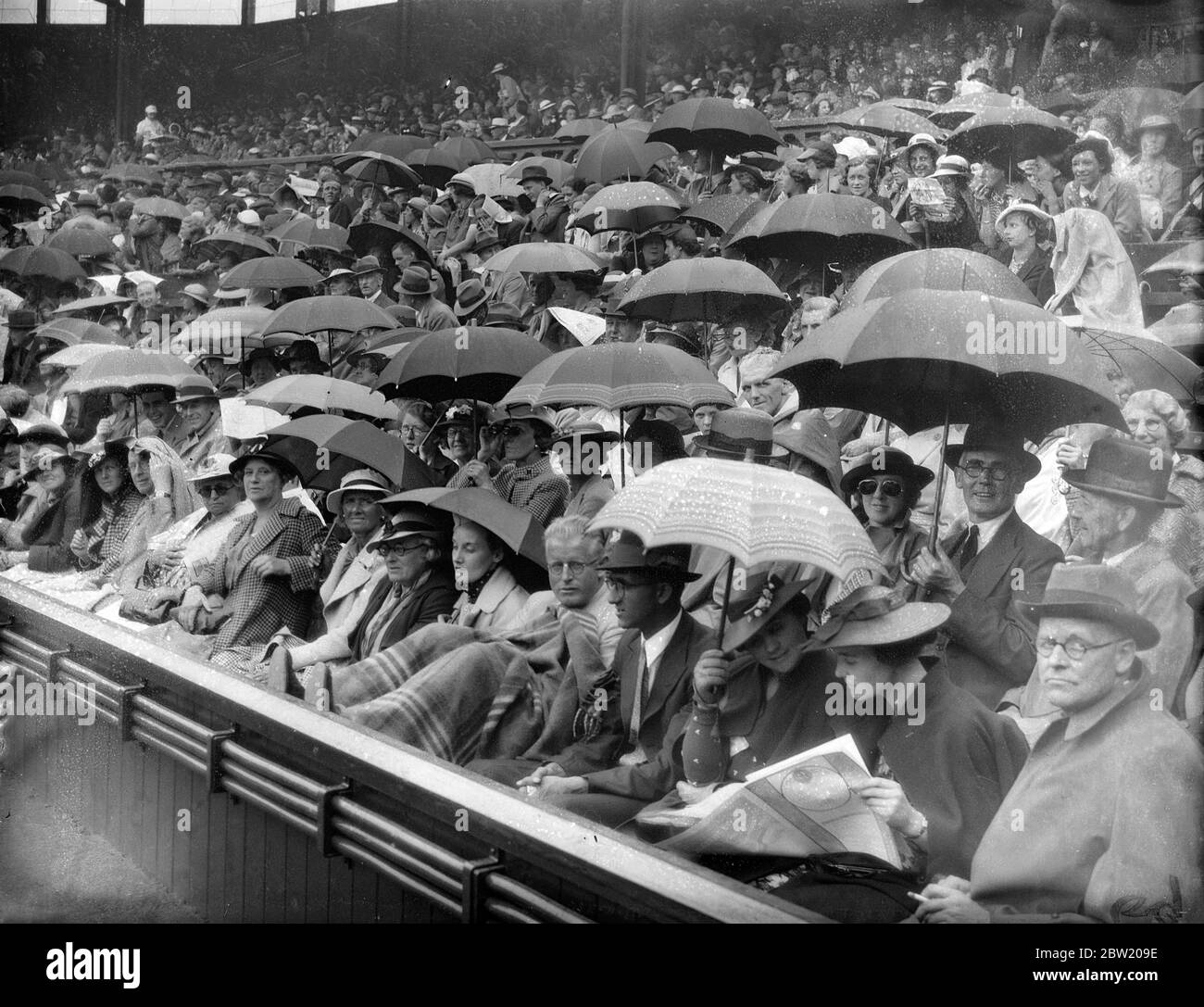 Por primera vez desde que comenzó el campeonato, la lluvia dejó de jugar en la Corte Central de Wimbledon, durante el partido entre la FRU Sperling, la favorita danesa para el título femenino, y la Srta. Alice Marble, la campeona de mujeres de Estados Unidos. Paraguas que protegen a la multitud en el Tribunal Central. 29 de junio de 1937 Foto de stock