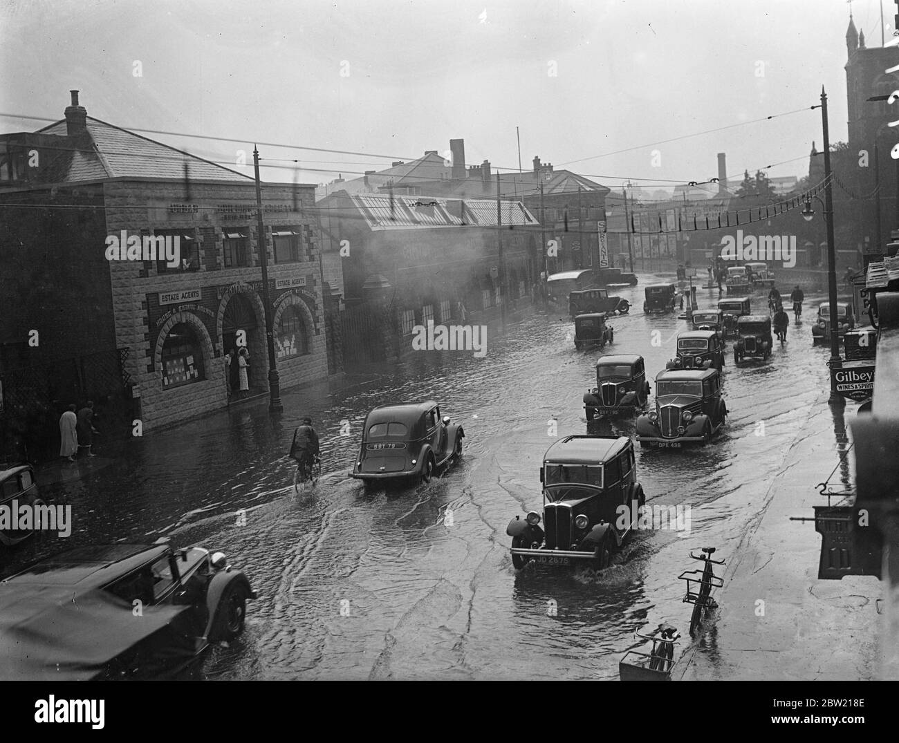 El tráfico que se araba a través de la inundada London Road en una calle Kingston después de la tormenta que estalló sobre los condados de origen e inundó la ciudad. 13 de julio de 1937. Foto de stock