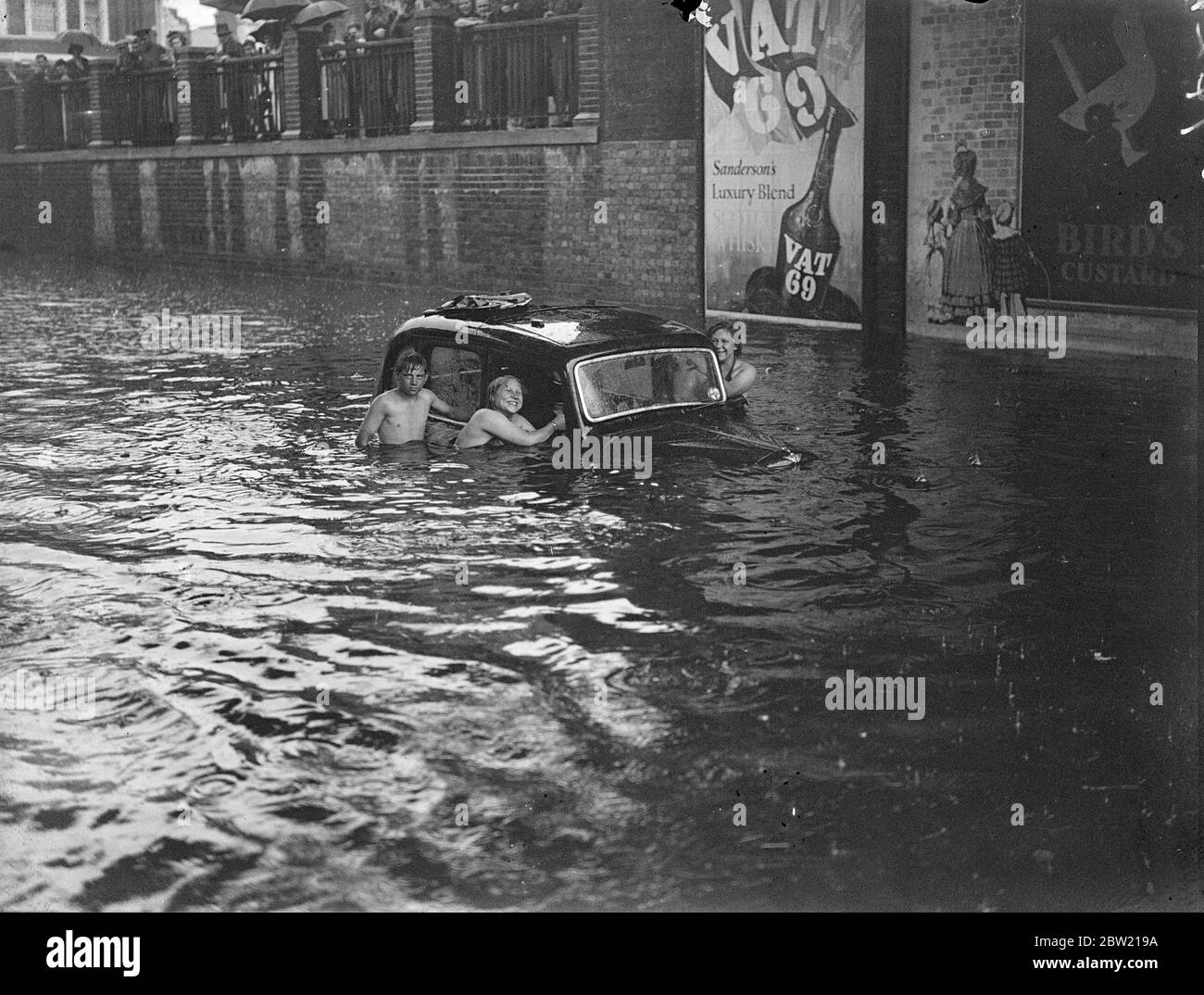 Nadadores alrededor de vehículos sumergidos en las mayores inundaciones registradas en Kingston, la ciudad ocupada y la carretera de Portsmouth fueron inundados después de la tormenta que estalló de repente en los condados de Home. 13 de agosto de 1937. Foto de stock